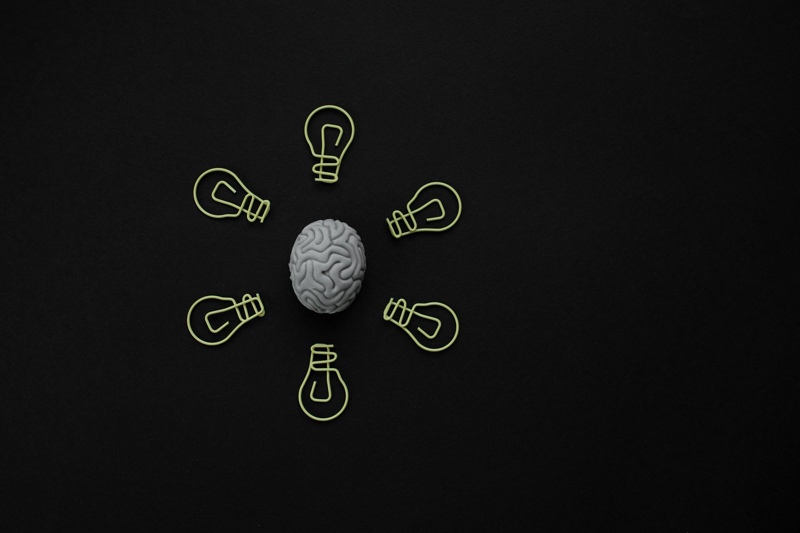 Conceptual photo of a brain surrounded by light bulb clips on black background.